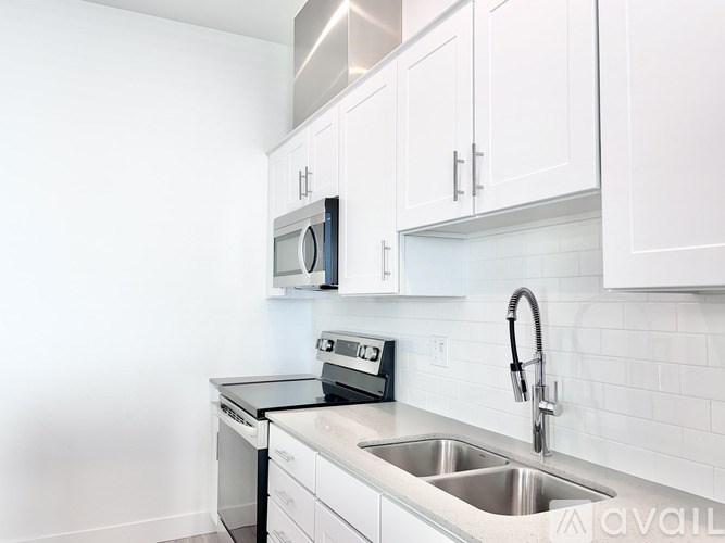 A kitchen with white cabinets and a stainless steel sink.