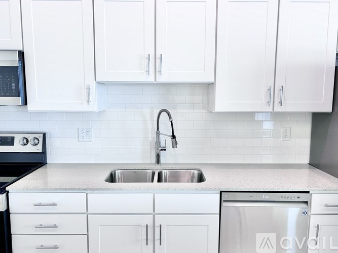 A kitchen with white cabinets and a stainless steel sink.