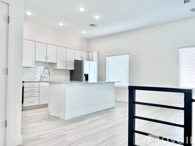 A modern kitchen with white cabinets and a black railing.