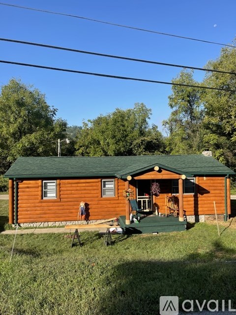 A small wooden cabin with a green roof and a porch.