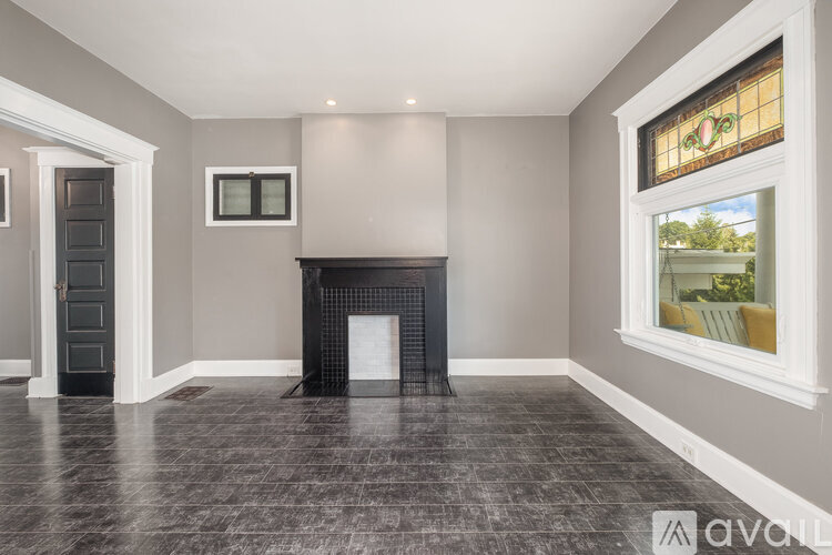 A room with a fireplace and a window showing a garden outside.