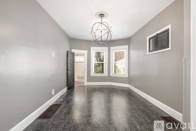 A spacious room with a wooden floor and a chandelier hanging from the ceiling.