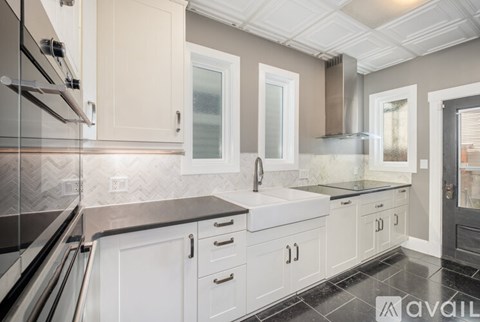 A kitchen with white cabinets and a black countertop.