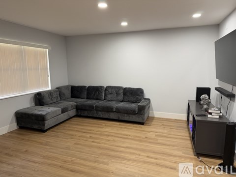 A grey sectional sofa in a living room with wooden flooring and a television.