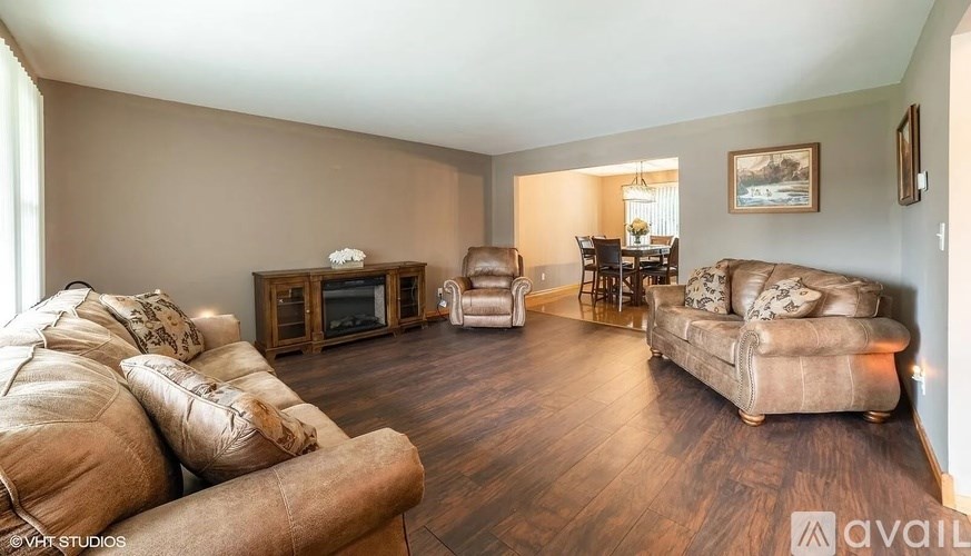 A living room with a sofa, armchair, and a table with a lamp.