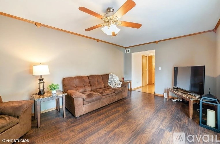 A living room with a brown couch and a ceiling fan.