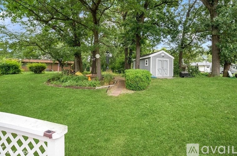 A backyard with a white fence, a shed, and a tree.
