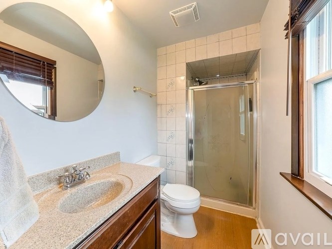 A bathroom with a toilet, sink, mirror, and shower.