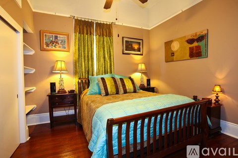 A bedroom with a bed, two lamps, and a painting on the wall.