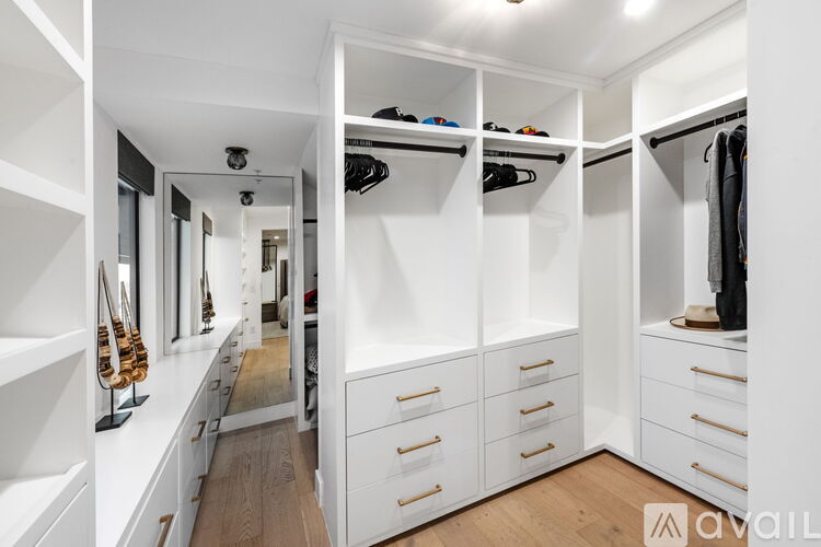 A spacious walk-in closet with white shelving and drawers.