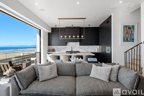 A living room with a grey sofa and a view of the ocean.