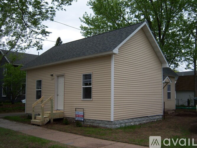 A small house with a porch and a sign in front of it.