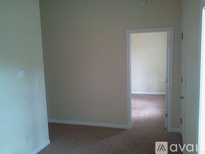 A room with a carpeted floor and a doorway leading to another room.