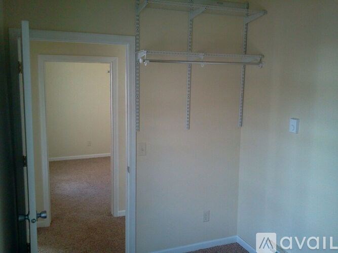 A room with a white door and a white wall with a shelf above it.