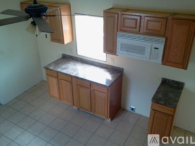 A kitchen with a fan, microwave, and wooden cabinets.