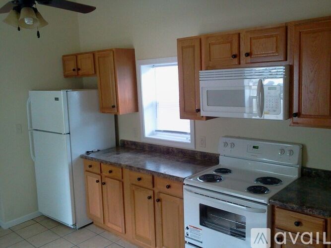 A kitchen with white appliances and wooden cabinets.
