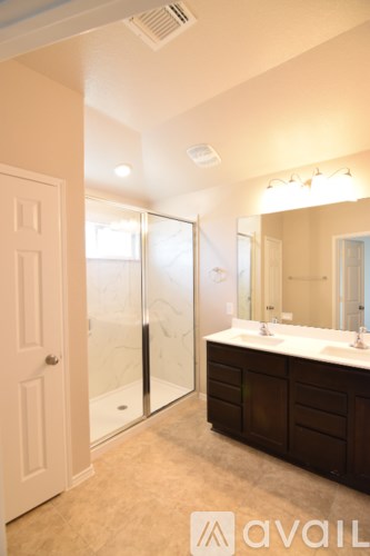 A bathroom with a sink, mirror, and shower.