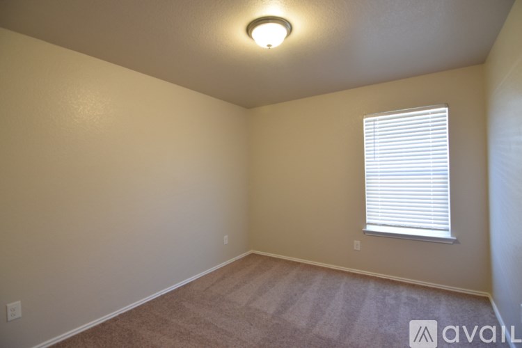 A room with a carpeted floor, a window with blinds, and a ceiling light fixture.