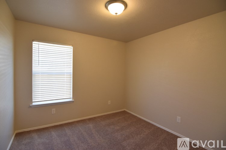 A room with a carpeted floor, a window with blinds, and a ceiling light fixture.