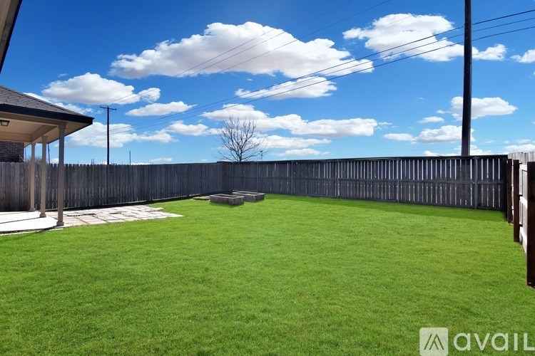 A backyard with a wooden fence and a small tree.