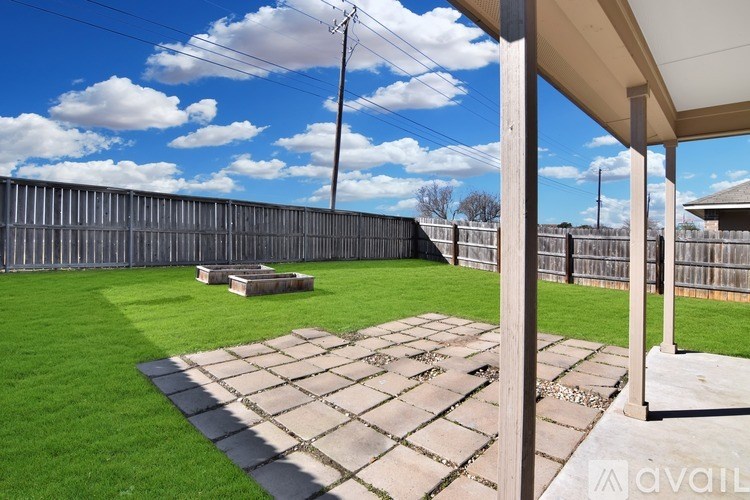 A backyard with a patio and a fence.