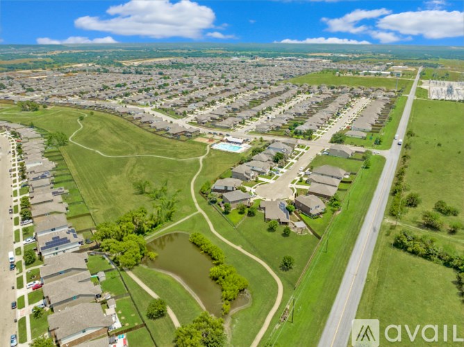 A bird's eye view of a residential area with houses, roads, and a small pond.