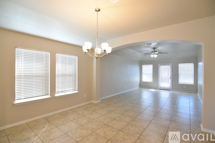 A spacious room with tiled flooring and a chandelier.