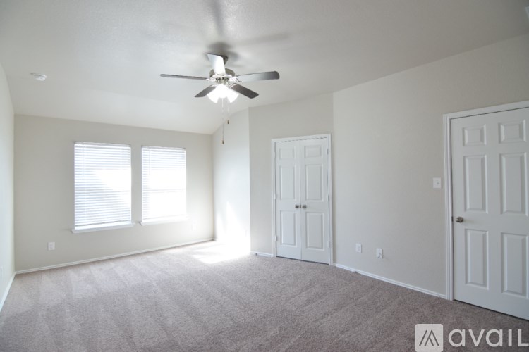 A spacious room with a ceiling fan and two doors.