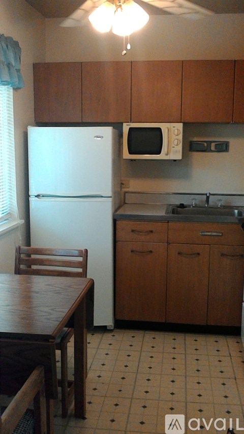 A kitchen with a white refrigerator, wooden cabinets, and a ceiling fan.