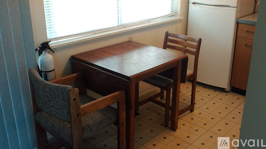 A wooden dining table with two chairs in front of a window.