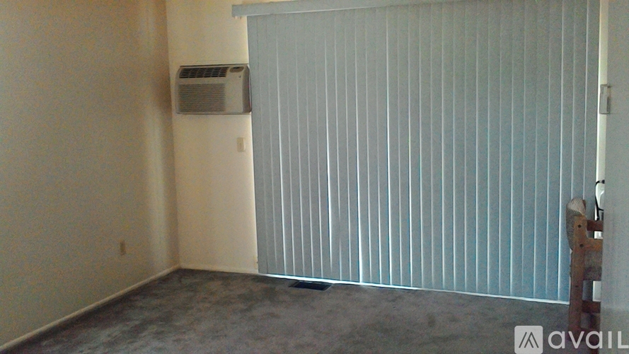 A room with a window covered by blinds and a wall-mounted air conditioner unit.