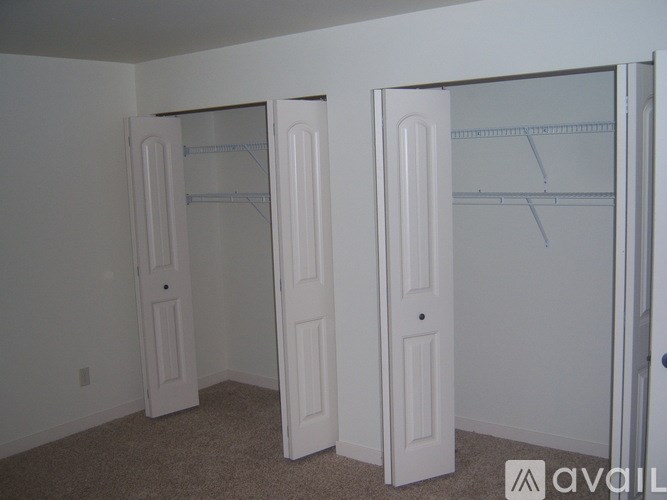 Two white closet doors with shelves in a room.