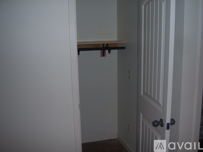 A white door with a black handle and a wooden shelf above it.