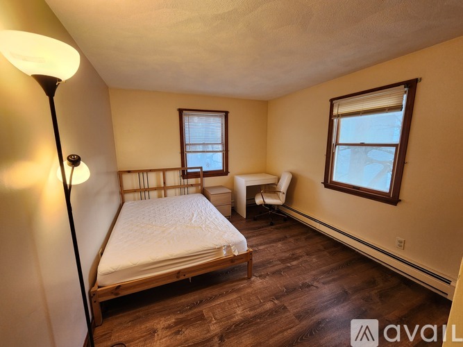 A bedroom with a bed, chair, and window.