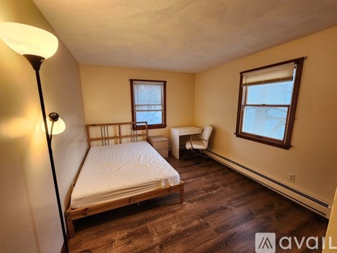A bedroom with a bed, chair, and window.