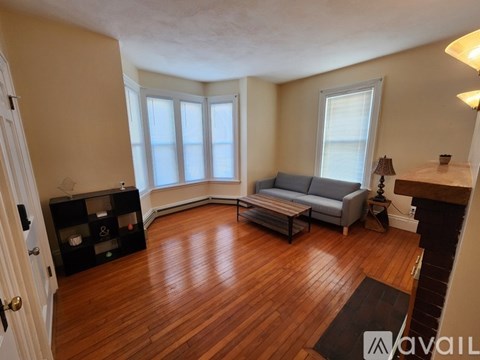 A living room with a grey couch and wooden floors.