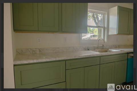 A kitchen with green cabinets and a marble countertop.