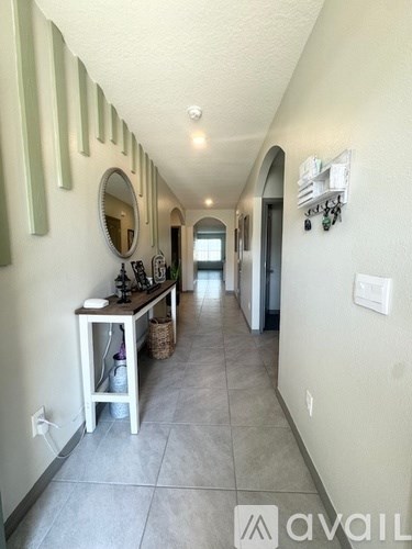 A hallway with a mirror and a table with a basket underneath it.