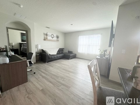 A living room with a black couch and a wooden floor.