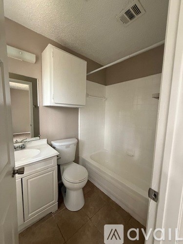 A white toilet sits in a bathroom next to a sink.
