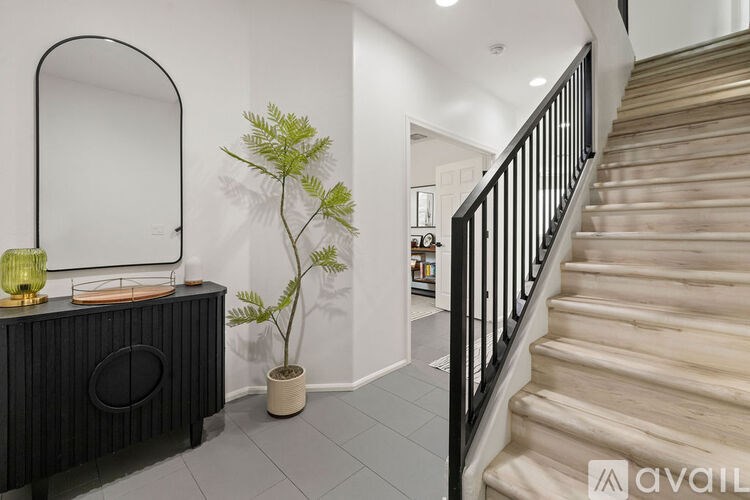 A black console table with a mirror and a green plant on it.