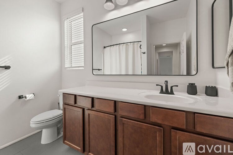 A bathroom with a toilet, sink, and mirror.