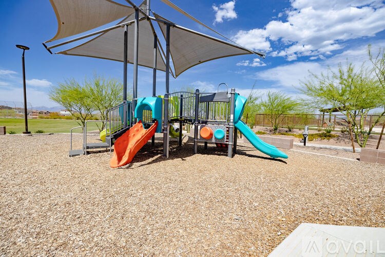 A playground with a blue and orange slide under a shade structure.