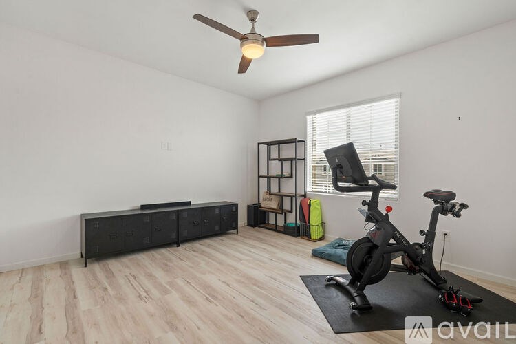 A room with a fan, a bicycle, and a black cabinet.