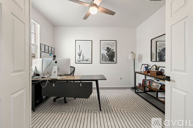 A room with a desk, chair, and a fan.