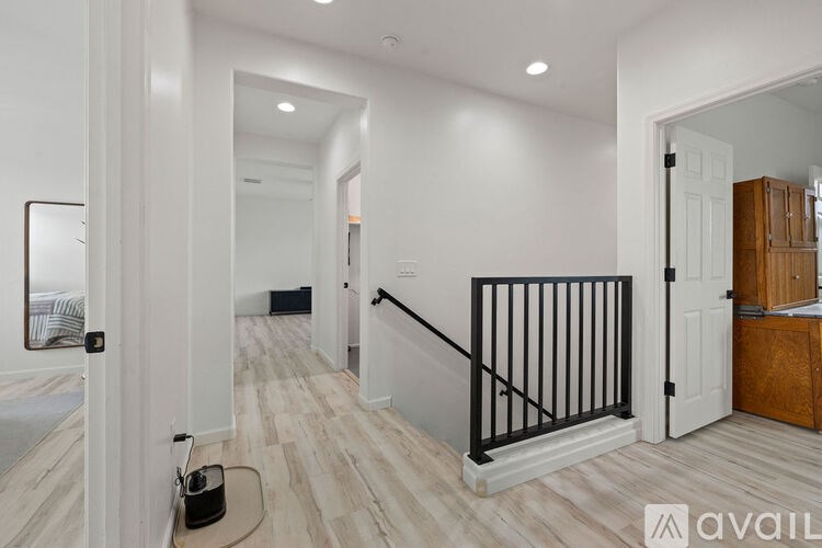 A hallway with a black railing and a white wall.