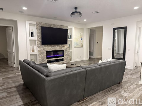 A modern living room with a grey sofa and a stone fireplace.