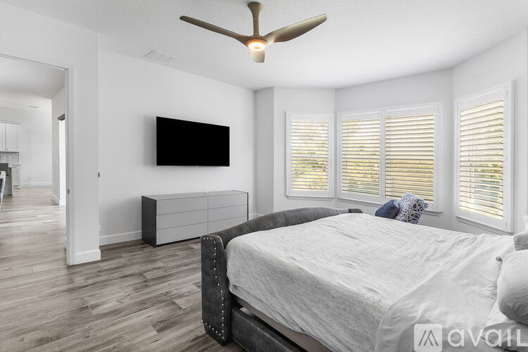 A bedroom with a large bed and a ceiling fan.