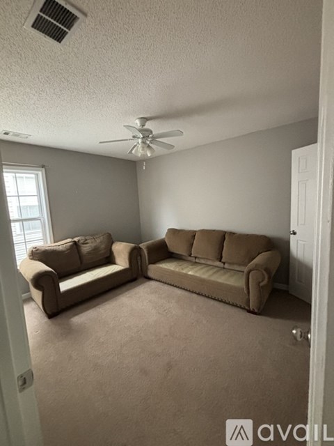 A living room with a beige couch and a ceiling fan.