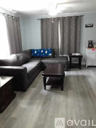 A living room with a grey couch and a brown table.